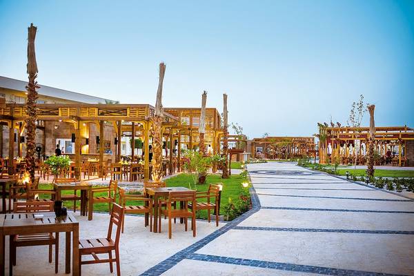Außenbereich des LABRANDA Royal Makadi Hotels mit gedeckten Holztischen und Stühlen.