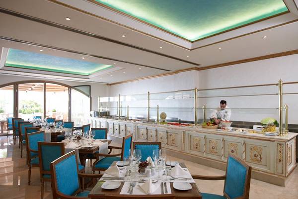 Innenansicht des Restaurants im Mitsis Laguna Resort mit einem Koch, der hinter dem Buffet steht.