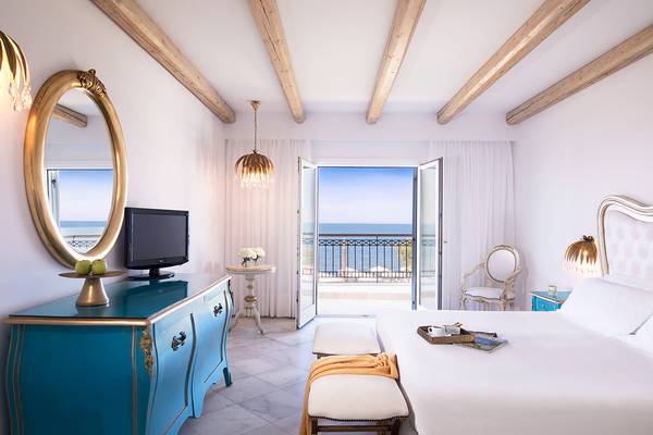 Innenansicht eines Zimmers im Mitsis Laguna Resort mit Blick auf das Meer und modernen Möbeln.