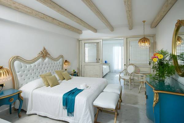 Schlafzimmer im Mitsis Laguna Resort mit weißen Möbeln, blauen Akzenten und einem großen Bett.