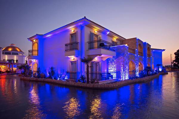 Mitsis Laguna Resort bei Nacht mit blauen Beleuchtung und Wasserreflexion