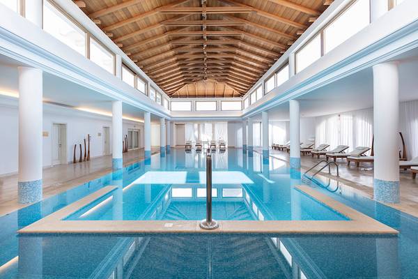 Innenpool im Mitsis Laguna Resort mit weißen Säulen und Holzdecke
