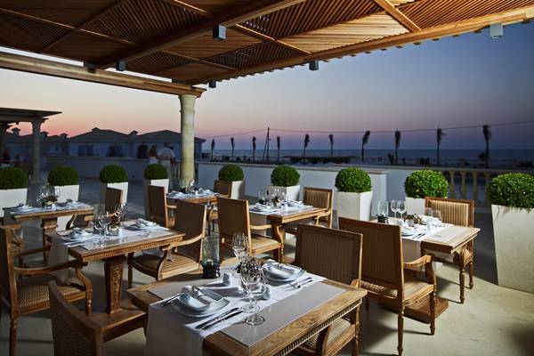 Terrassenrestaurant des Mitsis Laguna Resorts mit Blick auf den Ozean und Sonnenuntergang.