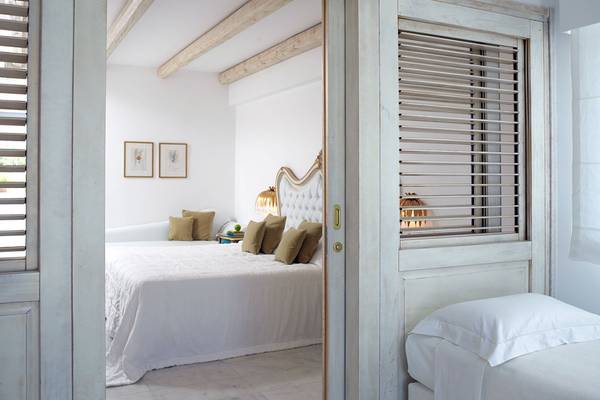 Innenansicht eines Schlafzimmers im Mitsis Laguna Resort mit einem Bett, Kissen und dekorativen Elementen.