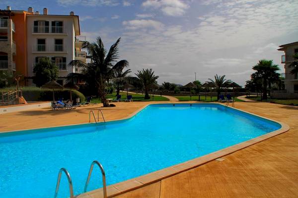 Ein Swimmingpool des Agua Hotels Sal Vila Verde mit Loungestühlen und Palmen.
