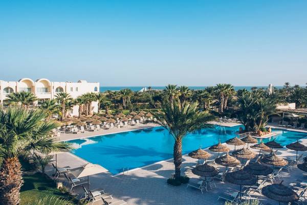 Aussenbereich des Iberostar Mehari Djerba Resorts mit Swimmingpool, Liegestühlen und Palmen.