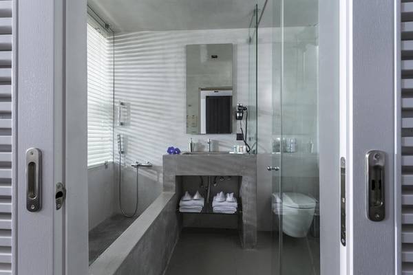 Ein modernes Badezimmer des Aeolos Beach Resort auf Korfu mit einer Dusche, Waschbecken und Toilette.