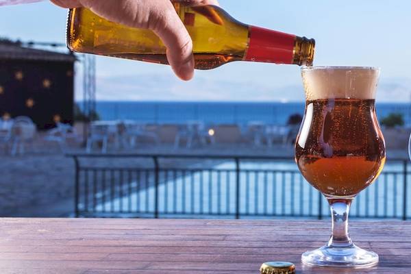 Hand gießt Bier in ein Glas im Aeolos Beach Resort auf Korfu