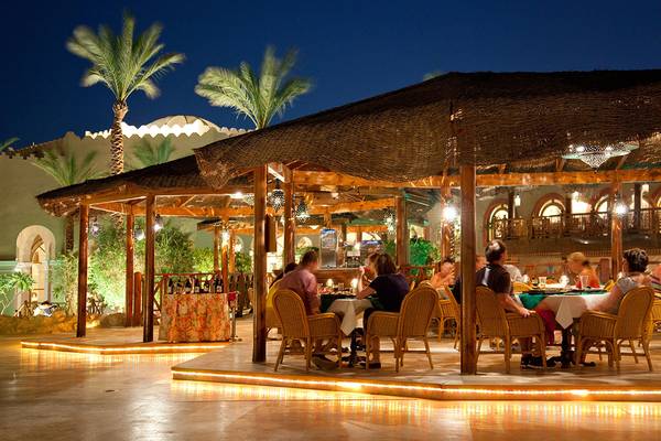 Gäste sitzen bei Nacht in einem beleuchteten Außenbereich des Ghazala Gardens Hotels.