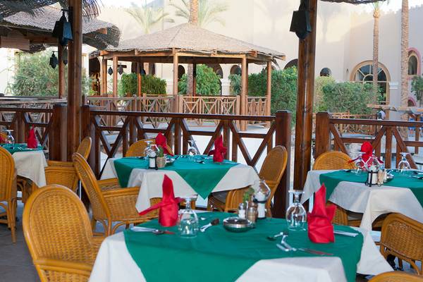 Außenbereich des Ghazala Gardens Hotels mit gedeckten Tischen und Palmen im Hintergrund.