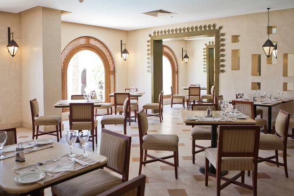 Innenbereich des Ghazala Gardens Restaurants mit runden Bögen, Tischen und Stühlen.