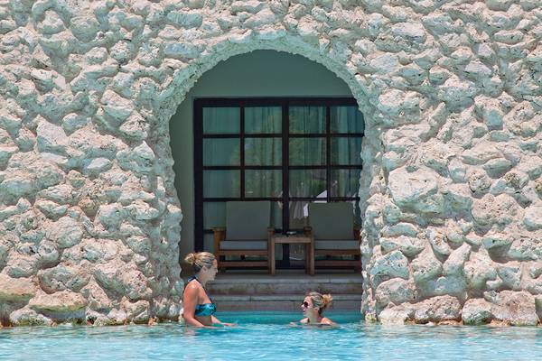 Zwei Frauen schwimmen im Pool des Ghazala Gardens Hotels, vor einem gemauerten Eingang.