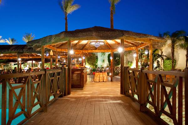 Nachtansicht der Bar im Ghazala Gardens Hotel mit beleuchteten Pavillon und hölzernem Steg.