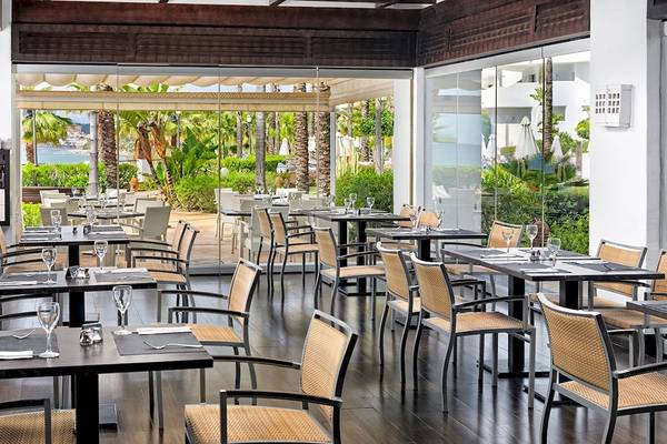 Innenansicht des Restaurants im H10 Estepona Palace mit Blick auf den Garten und das Meer.