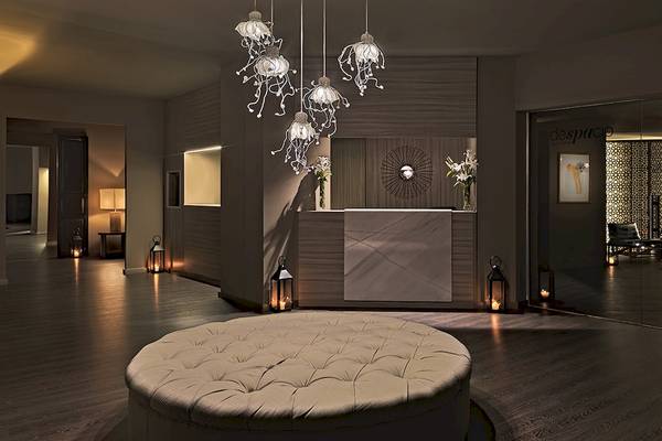Empfangshalle des H10 Estepona Palace mit modernen Lampen und einem großen Sofa.
