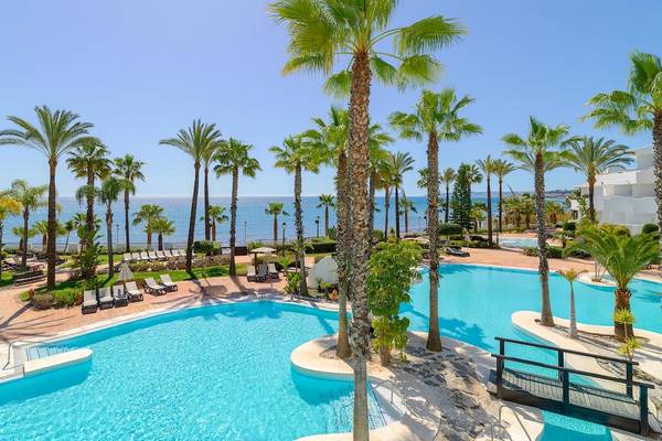 Außenpool des H10 Estepona Palace mit Palmen und Blick auf das Meer