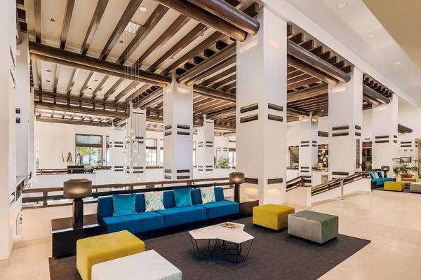 Innenansicht des H10 Estepona Palace Lobbys mit blauem Sofa und gelben Hockern.