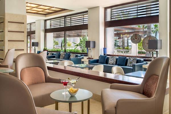 Lobby-Lounge-Bereich des H10 Estepona Palace mit modernen Möbeln und großen Fenstern.