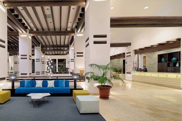 Lobby des H10 Estepona Palace mit blauer Couch, gelben Hockern und Empfangstresen