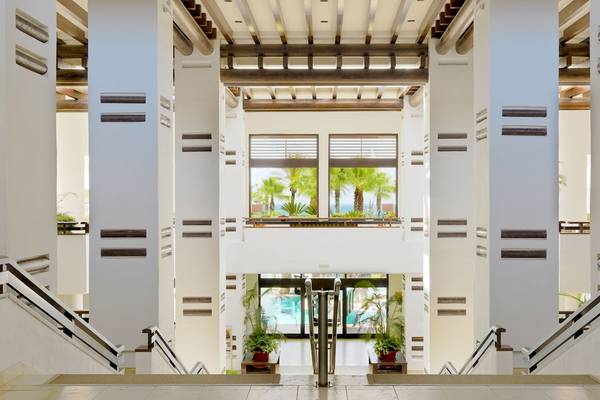 Innenansicht der Lobby im H10 Estepona Palace mit hohen Säulen und Glasfenstern.
