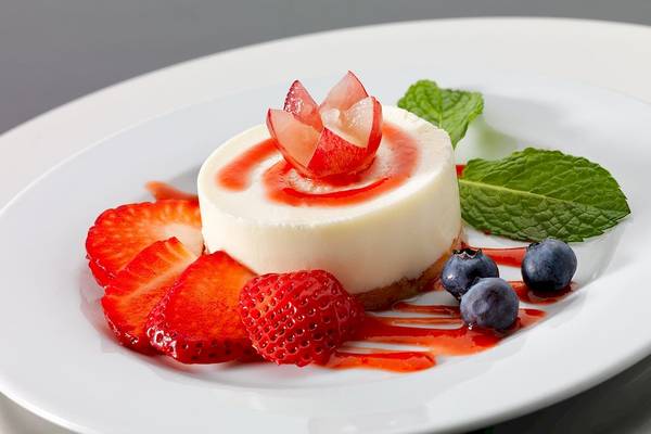 Dessert im H10 Estepona Palace Hotel mit Käsekuchen, Früchten und Minzblättern.