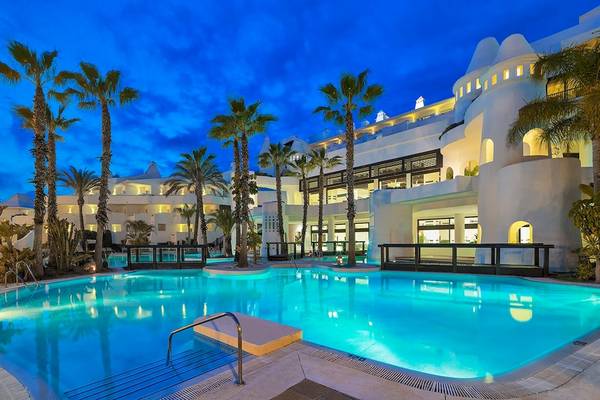 Außenpool des H10 Estepona Palace bei Nacht mit beleuchtetem Hotelgebäude und Palmen.