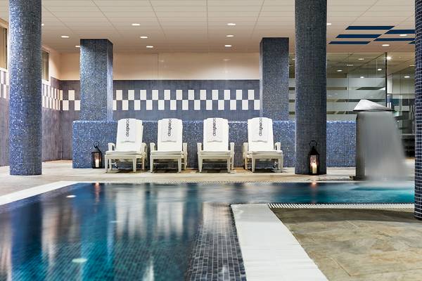 Innenpool des H10 Estepona Palace mit weißen Liegen und blauen Säulen