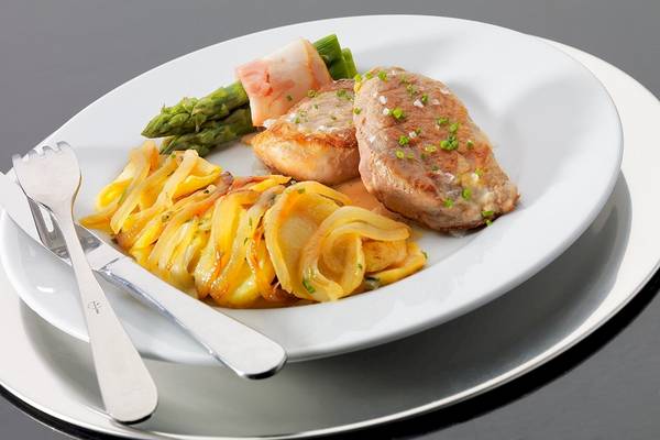 Gericht auf einem weißen Teller im H10 Estepona Palast Hotel mit Fleisch, Gemüse und Beilagen.