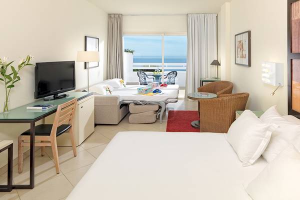 Doppelzimmer im H10 Estepona Palace mit Meerblick, inklusive Wohnzimmer, zwei Betten, Balkon und Fernseher.