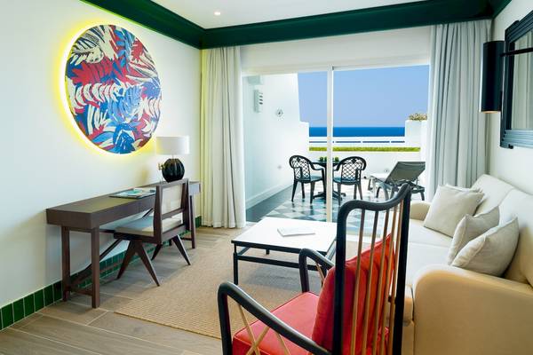 Wohnzimmer des H10 Estepona Palace mit Blick auf das Meer und modernen Möbeln.