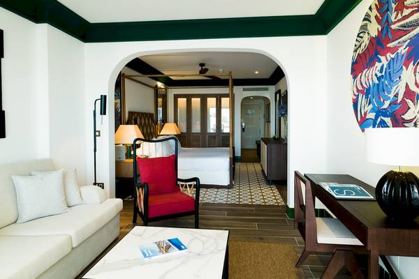 Innenraum der Suite im H10 Estepona Palace mit Wohnzimmer, Esstisch, Schlafzimmer und Dekoration.