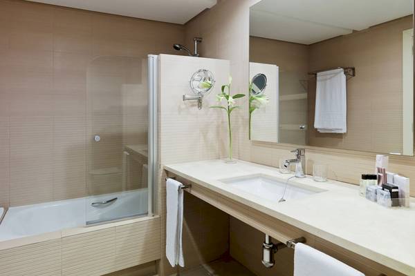 Badezimmer im H10 Estepona Palace mit Badewanne, Waschbecken und Spiegeln.