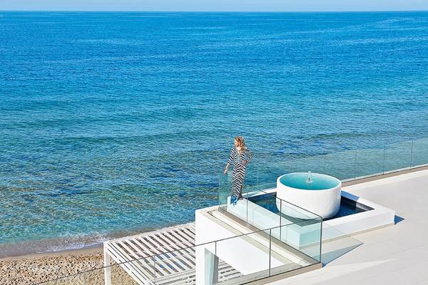 Frau auf Terrasse mit Aussicht auf das Meer vor dem Grecotel LUX ME White Palace