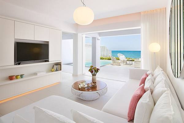 Innenbereich des Grecotel LUX ME White Palace Hotels mit Wohnzimmer und Meerblick.