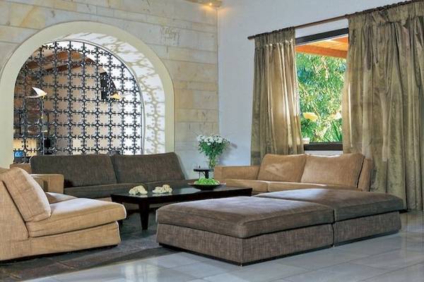 Apollonia Beach Resort & Spa Wohnzimmer mit Sofas, Tisch und Fenstern.