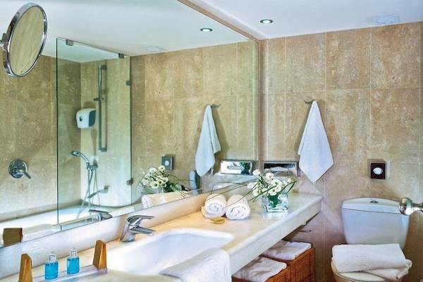 Badezimmer im Apollonia Beach Resort & Spa mit Spiegel, Waschbecken, Toilette und Handtüchern.