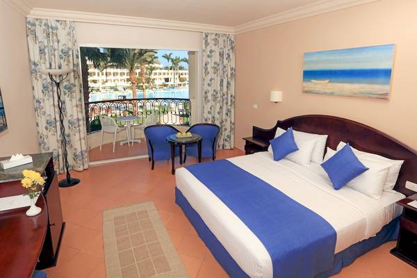 Hotelzimmer im LABRANDA Royal Makadi mit Blick auf den Pool und Palmen.