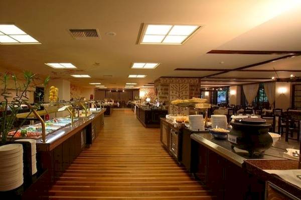 Buffetbereich des Apollonia Beach Resort & Spa mit verschiedenen Speisen und Holzboden.