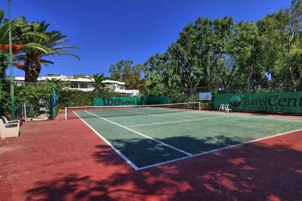 Tennisplatz im Apollonia Beach Resort & Spa mit grünem Rasen, weißen Linien und einer Wilson-Tafel.