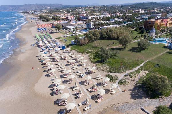 Luftaufnahme des Orpheas Resorts mit vielen Sonnenschirmen und Liegen am Strand.