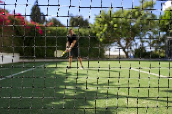 Tennisplatz im Freien im Grecian Sands Hotel mit Netz und spielender Person.