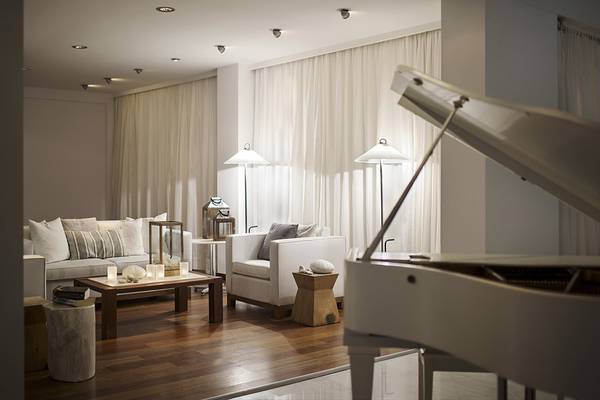 Wohnzimmer im Grecian Sands Hotel mit weißem Klavier, Sofas und Lampen.