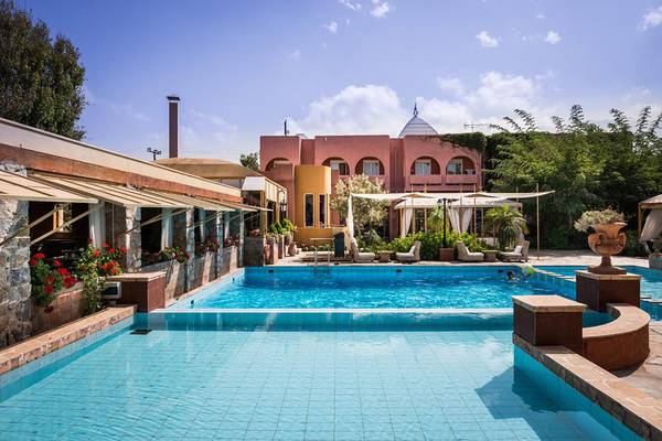 Außenpool des Orpheas Resorts im Sommer mit Hotelgebäude und Sonnenschirmen.