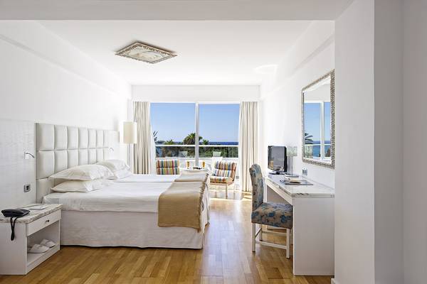 Griechisches Hotelzimmer mit Meerblick, weißen Möbeln und einem Schreibtisch