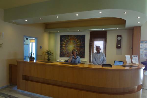 Rezeption des Europa Beach Hotel & Spa mit zwei Mitarbeitern, eines telefoniert, im Hintergrund eine große Wandmalerei.