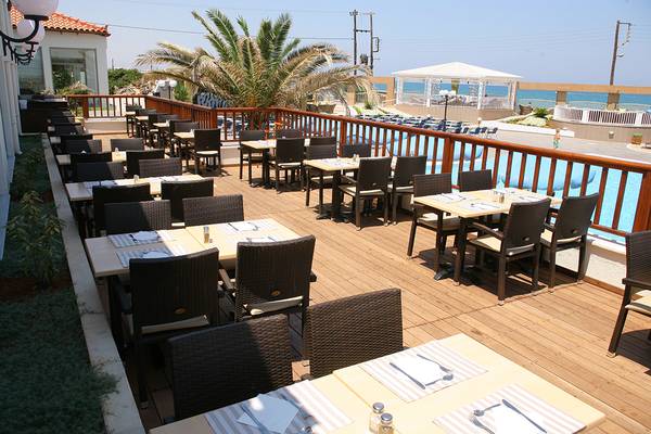 Terrasse des Europa Beach Hotel & Spa mit Tischen und Stühlen, Blick auf den Pool.