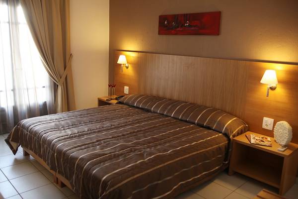 Doppelzimmer im Europa Beach Hotel & Spa mit einem Bett, Nachttischen und Wandleuchten.