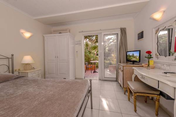 Schlafzimmer im Orpheas Resort mit Balkon, Fernseher, Tisch, Stühlen und Lampe
