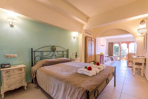 Hotelzimmer im Orpheas Resort mit Doppelbett, Nachttischen und Balkonzugang.