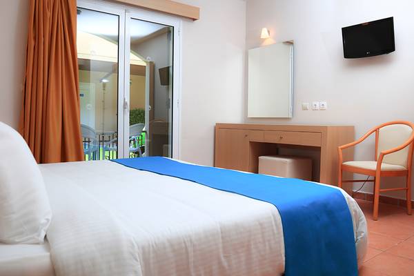 Innenansicht eines Hotelzimmers mit Bett, Nachttisch, Spiegel und Fernseher.